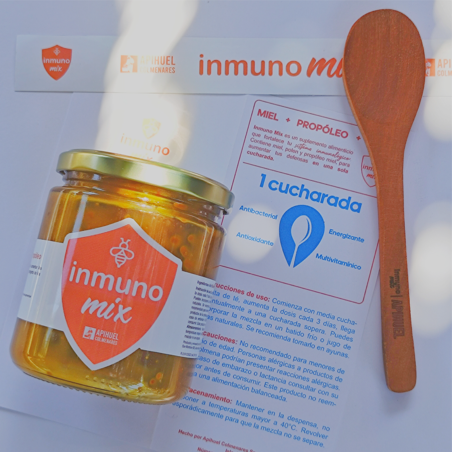 A jar of Inmuno Mix with a spoon, label, and logo, showcasing a blend of honey, energizing pollen, and propolis for immune support.