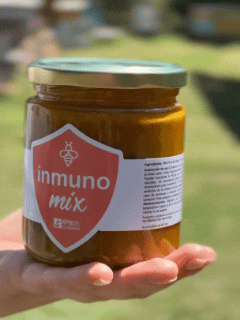 A hand holding a jar of Inmuno Mix food with a label, ideal for boosting immunity.